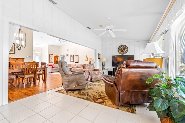 living room featuring ceiling fan with notable chandelier, light wood-type flooring, and lofted ceiling