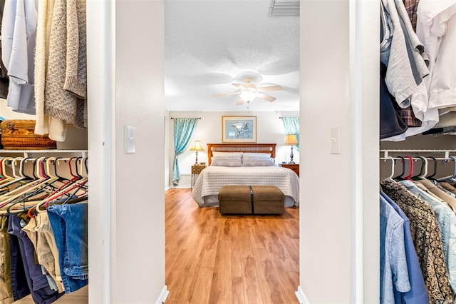 bedroom with hardwood / wood-style floors, a textured ceiling, and ceiling fan