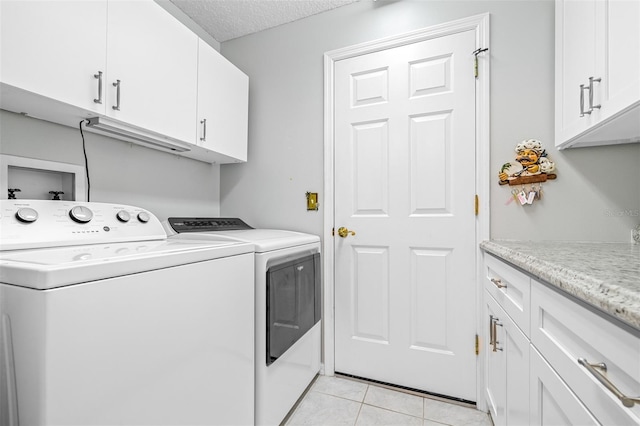 washroom featuring cabinets, separate washer and dryer, a textured ceiling, and light tile patterned floors