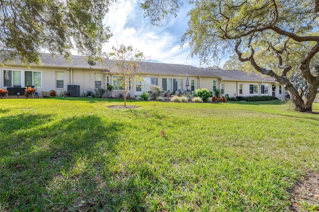 back of property featuring central AC and a lawn