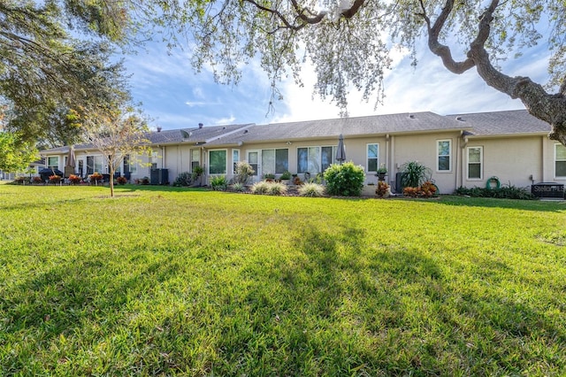 rear view of property with central AC and a yard