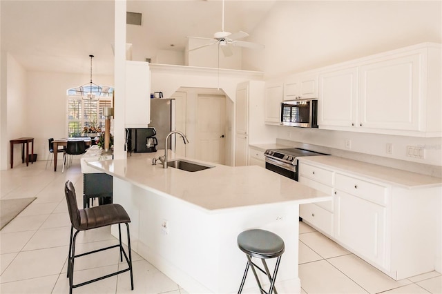 kitchen with sink, hanging light fixtures, stainless steel appliances, a kitchen breakfast bar, and high vaulted ceiling