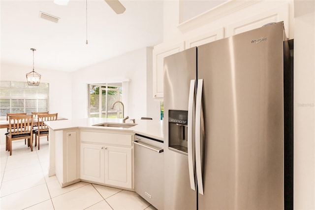 kitchen with appliances with stainless steel finishes, sink, light tile patterned floors, decorative light fixtures, and white cabinets