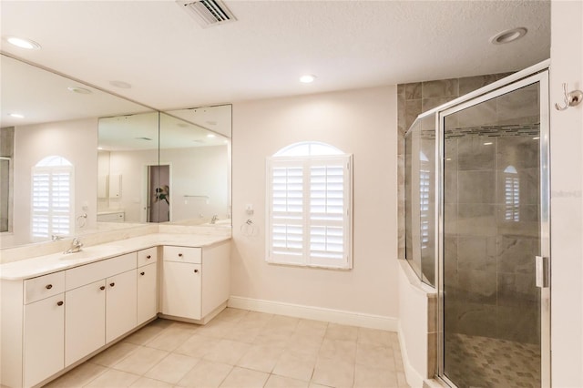 bathroom with tile patterned floors, vanity, a shower with door, and a textured ceiling