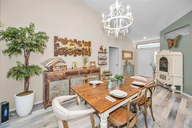 dining space with hardwood / wood-style flooring, lofted ceiling, and a chandelier