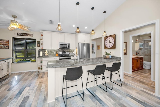 kitchen featuring light hardwood / wood-style flooring, stainless steel appliances, white cabinetry, and stone countertops