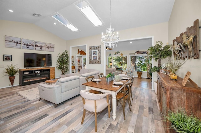 dining room featuring a chandelier, light hardwood / wood-style floors, and vaulted ceiling