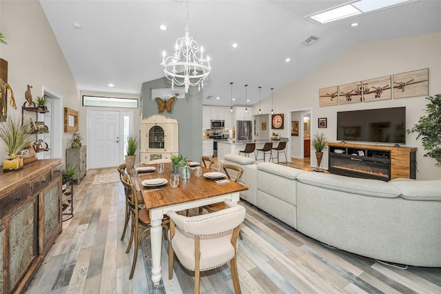 1012 Osprey Ct, Tarpon Springs, FL 34689 - dining room with light wood-style flooring, lofted ceiling, a chandelier, recessed lighting, and a glass covered fireplace