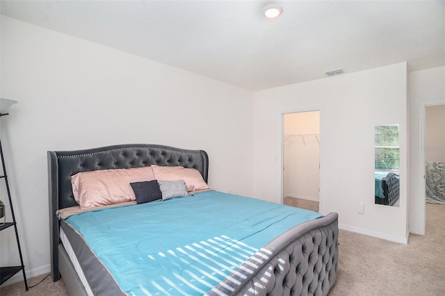 bedroom with a walk in closet, a closet, and light colored carpet