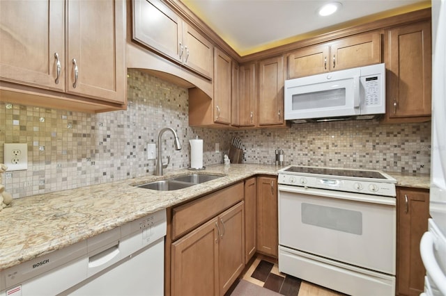 kitchen featuring backsplash, light stone counters, white appliances, and sink