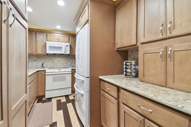 kitchen featuring backsplash, light stone countertops, white appliances, and hardwood / wood-style flooring