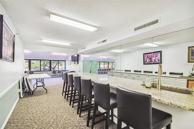 kitchen with a breakfast bar, decorative light fixtures, light stone counters, and sink