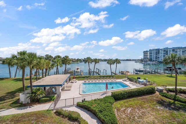 view of pool with a lawn, a water view, and a patio