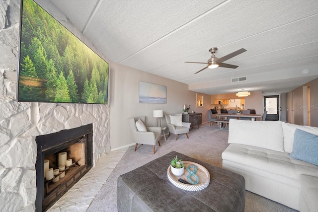 carpeted living room with a fireplace, a textured ceiling, and ceiling fan