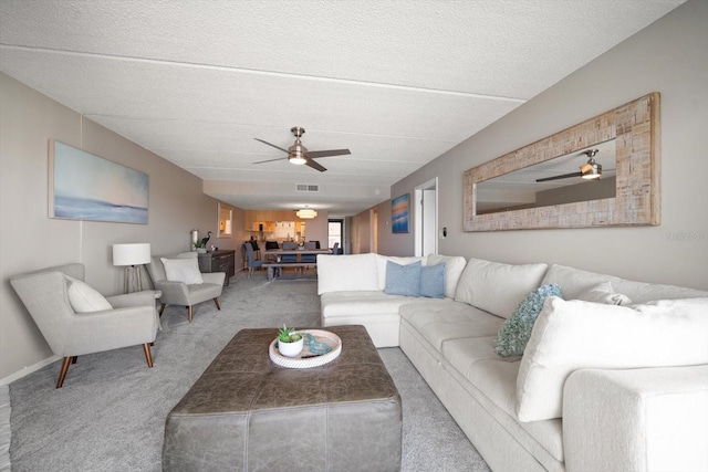 carpeted living room featuring ceiling fan and a textured ceiling