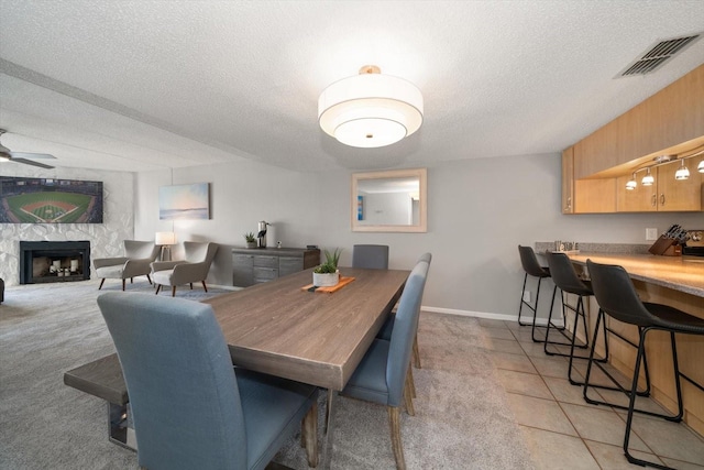 tiled dining space with ceiling fan and a textured ceiling