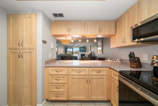 kitchen featuring kitchen peninsula, light brown cabinetry, light tile patterned floors, and stainless steel appliances