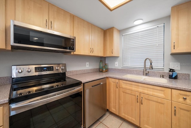 kitchen featuring sink, light tile patterned floors, light brown cabinets, and appliances with stainless steel finishes