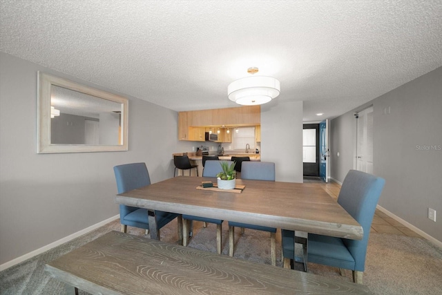 dining space featuring light carpet, a textured ceiling, and sink