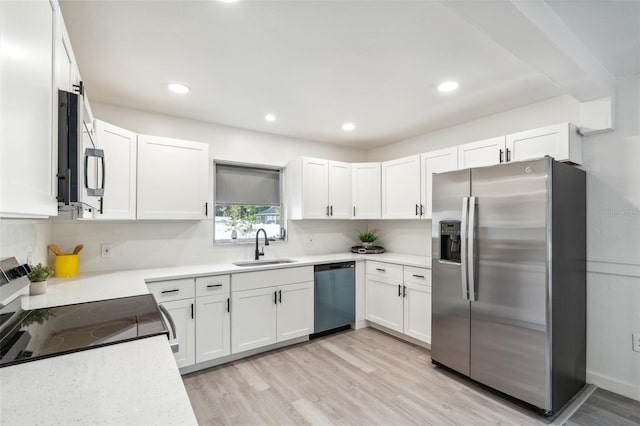 kitchen featuring a sink, stainless steel appliances, light wood-type flooring, and white cabinetry