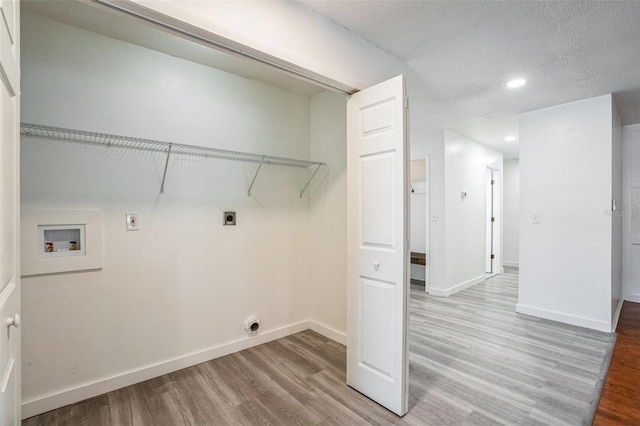 clothes washing area featuring hookup for an electric dryer, washer hookup, a textured ceiling, and hardwood / wood-style floors