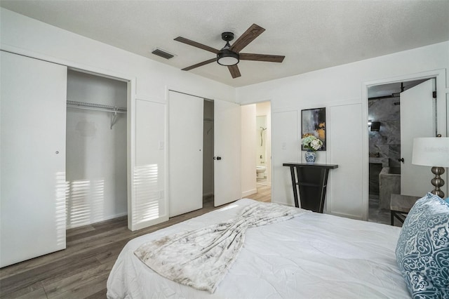 bedroom with hardwood / wood-style floors, a textured ceiling, ensuite bath, and ceiling fan