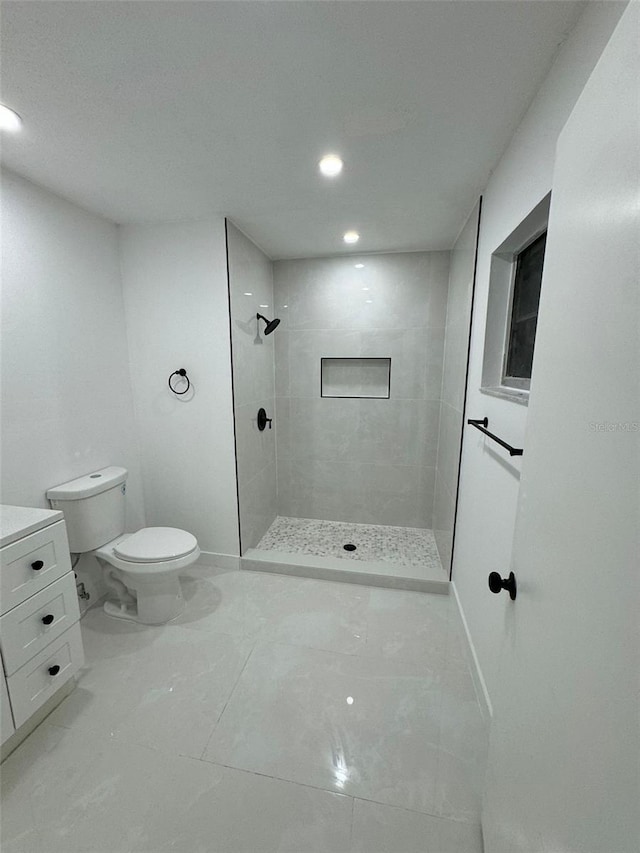 bathroom with toilet, marble finish floor, a tile shower, recessed lighting, and vanity