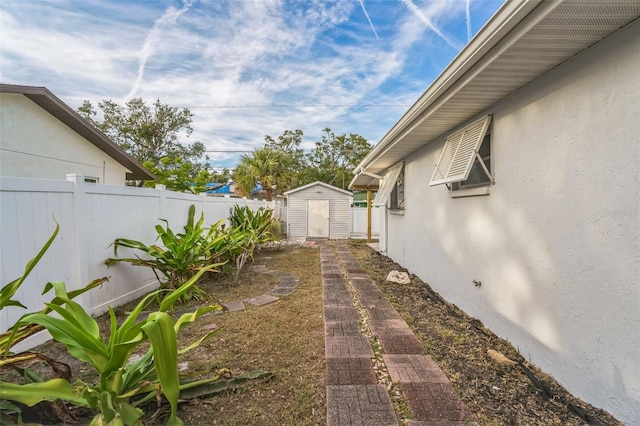 view of yard featuring a storage unit, a fenced backyard, and an outdoor structure