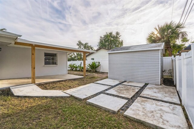 view of yard featuring an outbuilding, a storage unit, a patio area, and a fenced backyard