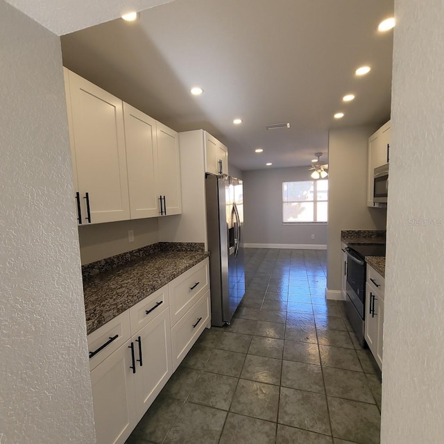 kitchen with dark stone counters, white cabinets, dark tile patterned flooring, ceiling fan, and appliances with stainless steel finishes