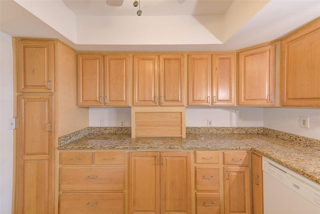 kitchen with a tray ceiling, light stone counters, light brown cabinets, and white dishwasher