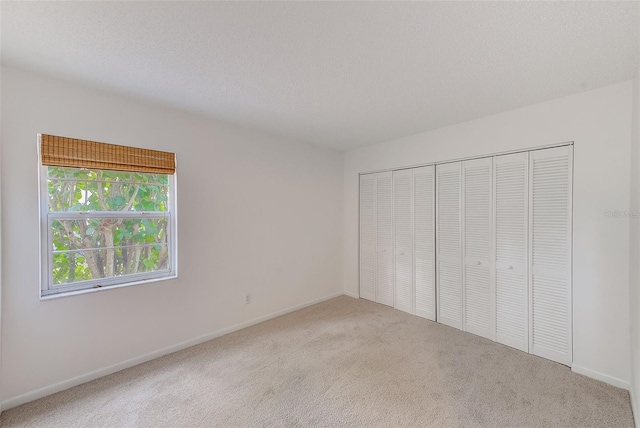 unfurnished bedroom featuring carpet, a textured ceiling, and a closet