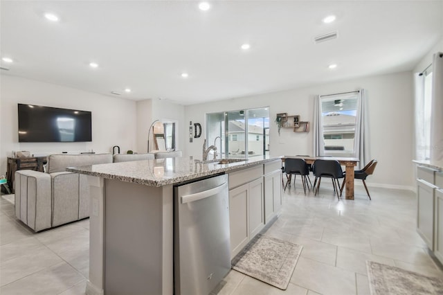 kitchen featuring light stone countertops, dishwasher, sink, a kitchen island with sink, and light tile patterned flooring