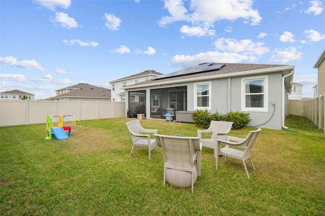 rear view of property with solar panels, a lawn, and a sunroom