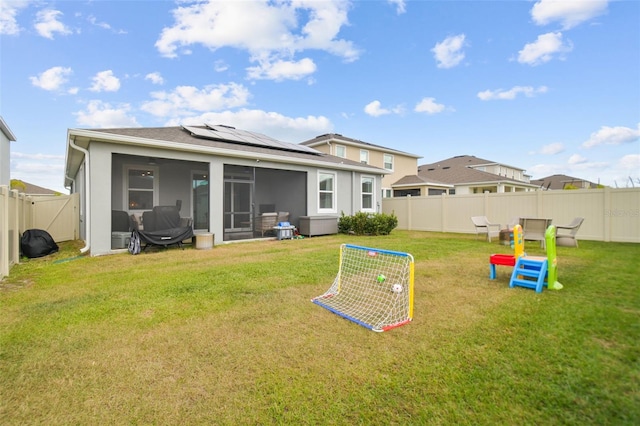 back of property featuring a sunroom, solar panels, and a lawn