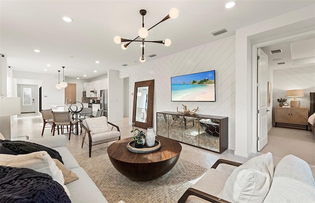 living area with an accent wall, a notable chandelier, recessed lighting, and visible vents