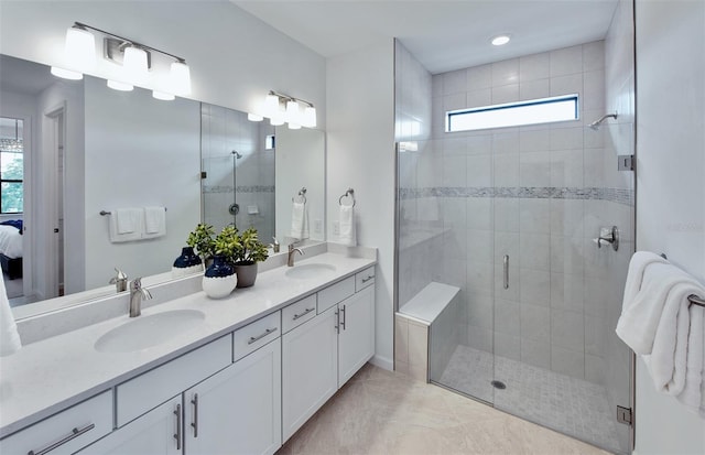 ensuite bathroom featuring tile patterned floors, a shower stall, and a sink