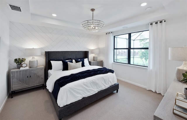 carpeted bedroom with a chandelier, visible vents, baseboards, and a tray ceiling