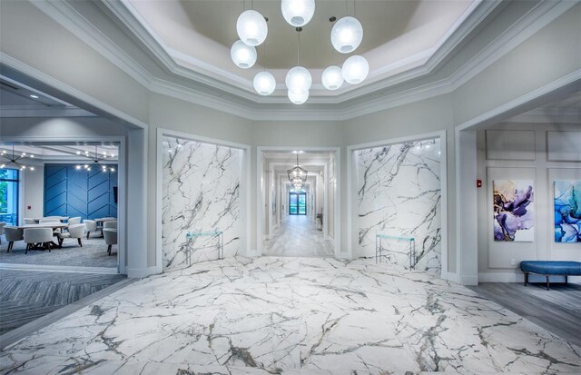 hall featuring a notable chandelier, crown molding, and a raised ceiling