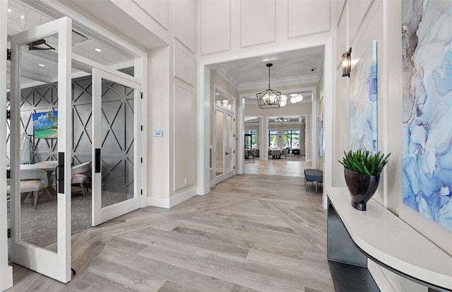 entryway with crown molding, baseboards, parquet flooring, french doors, and an inviting chandelier