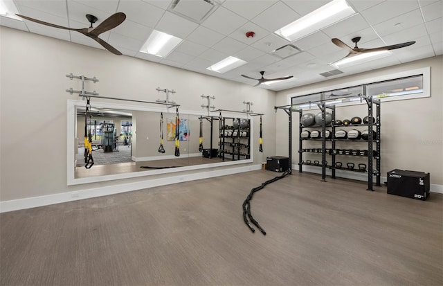 gym with visible vents, baseboards, ceiling fan, and a drop ceiling