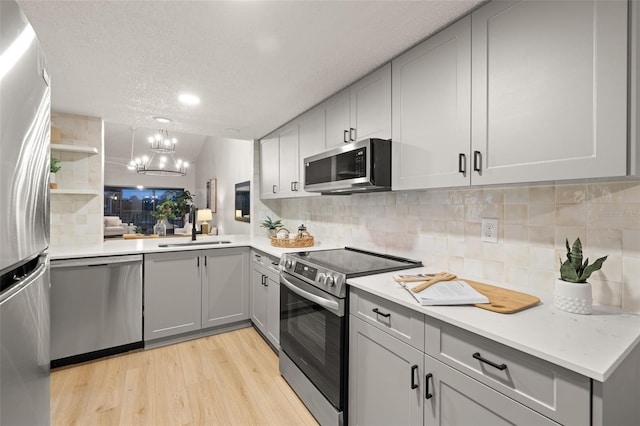 kitchen featuring sink, light hardwood / wood-style floors, a textured ceiling, and appliances with stainless steel finishes