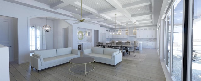 living room with ceiling fan with notable chandelier, light hardwood / wood-style flooring, beamed ceiling, and coffered ceiling