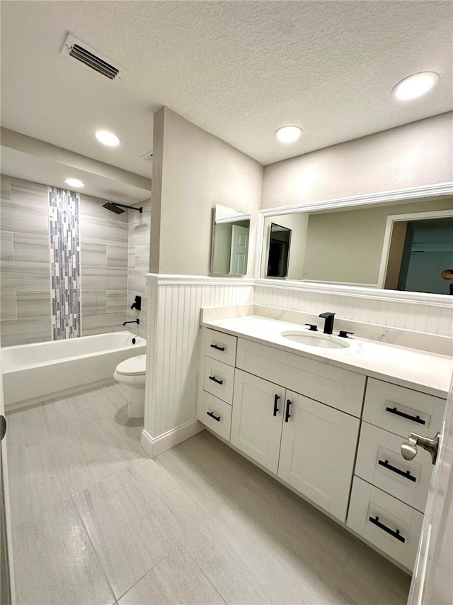 full bathroom featuring vanity, a textured ceiling, toilet, and tiled shower / bath