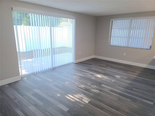 unfurnished room with a textured ceiling and dark wood-type flooring