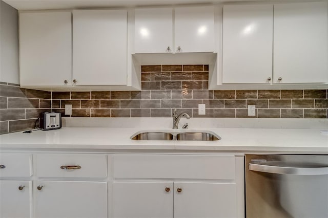 kitchen with white cabinets, decorative backsplash, stainless steel dishwasher, and sink