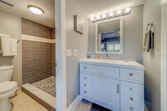 bathroom featuring tile patterned floors, a textured ceiling, toilet, tiled shower, and vanity