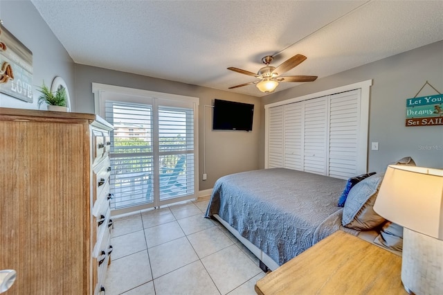 tiled bedroom with ceiling fan, access to exterior, and a textured ceiling