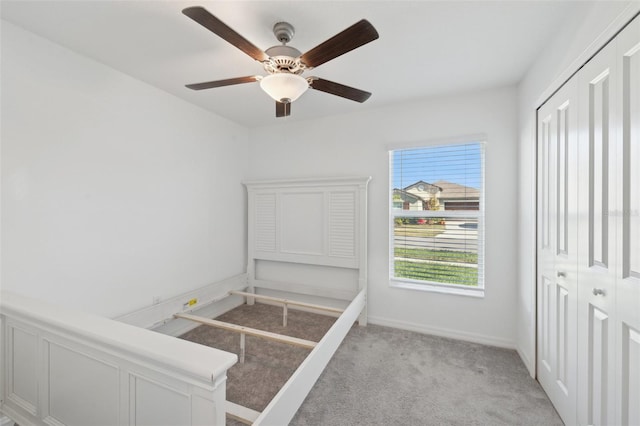 unfurnished bedroom featuring light carpet, a closet, and ceiling fan