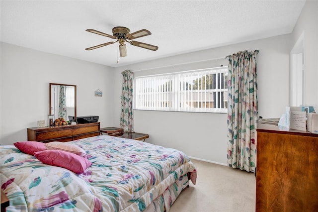 bedroom featuring multiple windows, ceiling fan, light colored carpet, and a textured ceiling